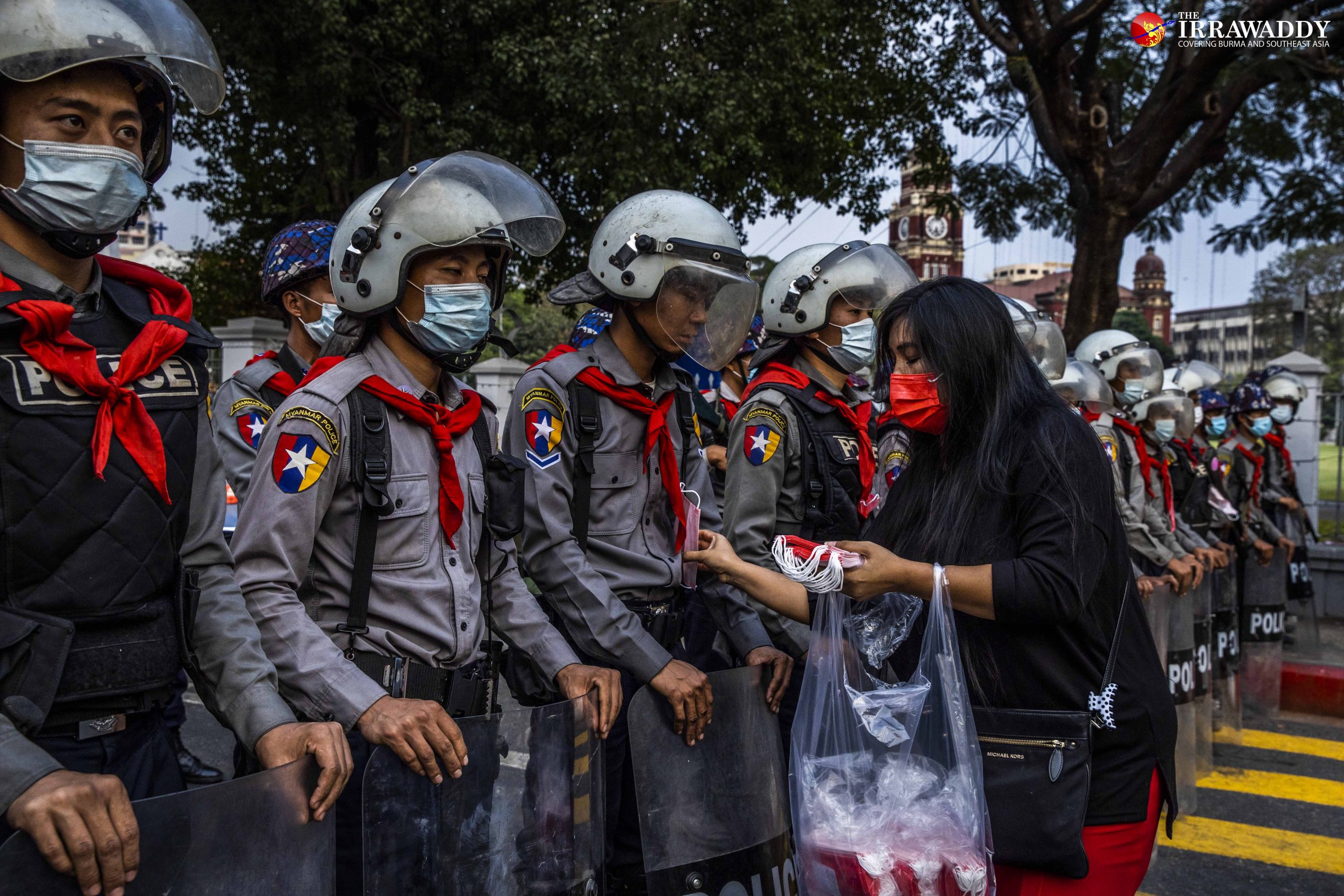 ၂၀၂၁ ဖေဖော်ဝါရီလ ရန်ကုန်တွင် စစ်အာဏာသိမ်းဆန့်ကျင်ရေး ဆန္ဒပြသူတဦးက ရဲများအား ကိုဗစ်ရောဂါကာကွယ်ရေး နှာခေါင်းစည်းများ ဝေငှစဉ် / ဧရာဝတီ