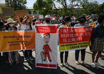 ၂၀၂၁ ခုနှစ်၊ ဖေဖော်ဝါရီလ ၁၁ ရက်နေ့က ရန်ကုန်ရှိ တရုတ်သံရုံးရှေ့တွင် စစ်အာဏာသိမ်းမှုကို ဆန့်ကျင်ဆန္ဒပြသူများက မင်းအောင်လှိုင်အပေါ် တရုတ်သမ္မတ ရှီကျင့်ဖျင်က ကြိုးကိုင်ထားပုံ သရုပ်ဖော်ပုံကို ကိုင်ဆောင်ထားစဉ် / AFP